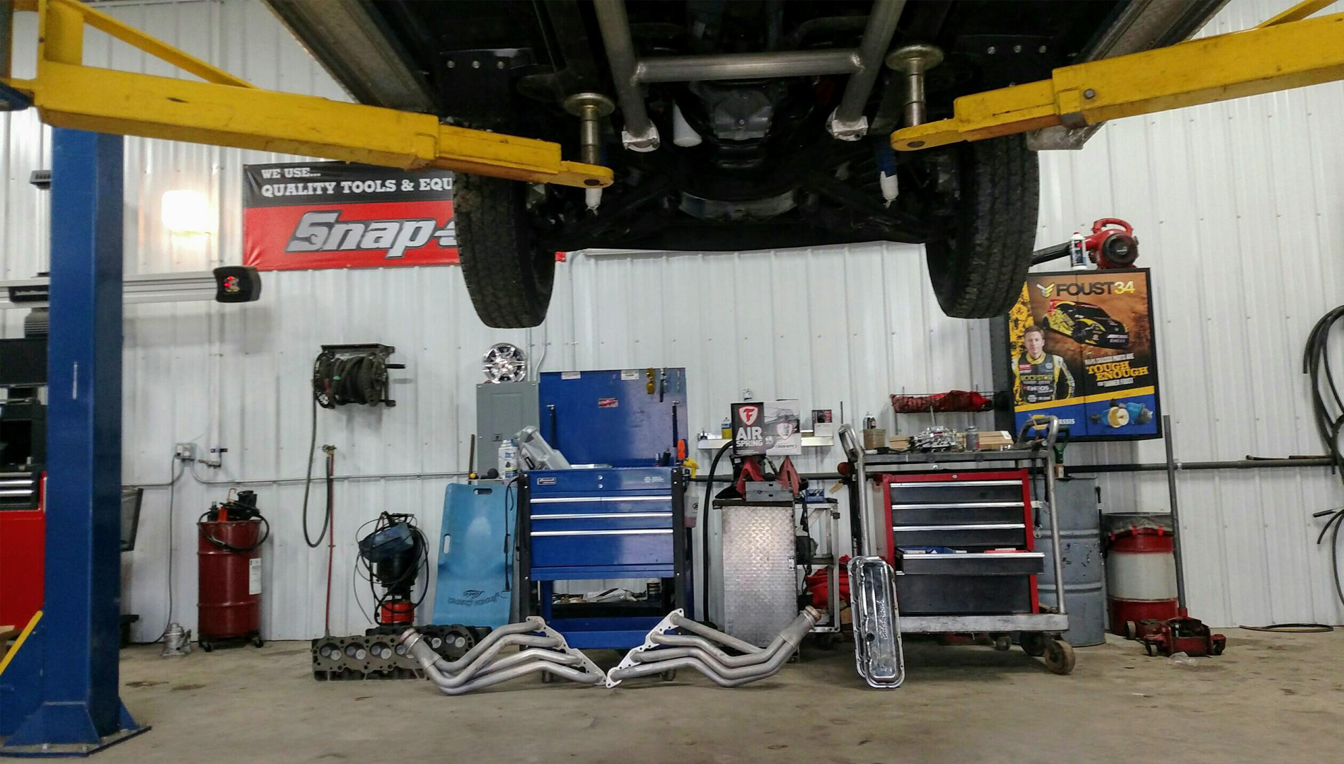 A vehicle on a lift and repair equipment inside the shop